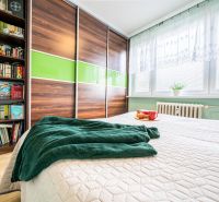 Bedroom in a two-room apartment with a bed, bookshelf, and built-in wardrobe with a wooden decor.