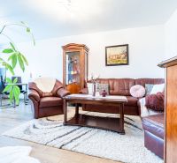 Living room in a two-room apartment with a leather sofa and a floor with a wooden decor.
