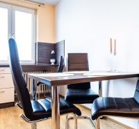 Dining area with black chairs, a table, and a wooden decor floor in a 2-room apartment.