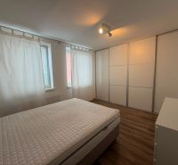 A bedroom with built-in wardrobes and a bed, complemented by a wooden decor floor in a two-room apartment.