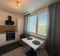 A kitchen in a 2-room apartment with a white kitchen unit and a view from the window.