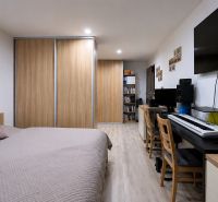 Bedroom in a 3-room apartment with built-in wardrobes, a desk, and a floor with a wooden decor.