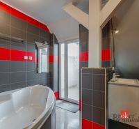 A bathroom with a bathtub and a sink in a 3-room apartment, featuring striking black and red tiles.
