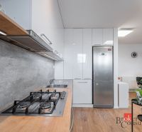 A kitchen in a 3-room apartment with a stainless steel refrigerator and a cooktop, flooring with a wood decor.