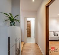 A hallway with an entrance to the living room and a wooden decor floor in a 3-room apartment.