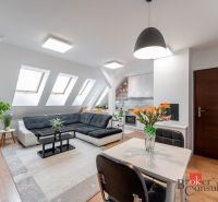 Living area of a 3-room apartment with a sofa, table, and wooden decor flooring.