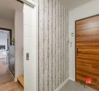 A hallway of a 3-room apartment with wooden doors and a floor with a wooden decor.