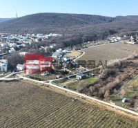Aerial view of vineyards and houses in the Záhrad area in Bratislava III, surrounded by hills.
