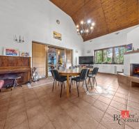 Living room in a family house with a fireplace, piano, and dining table.
