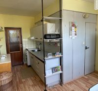 A kitchen in a 2-room apartment with a wooden decor floor and yellow walls.