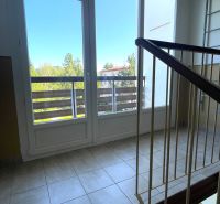 A corridor with a balcony in a 2-room apartment with a view of the trees.