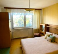 Bedroom in a 2-room apartment with a double bed, large window, and curtains.