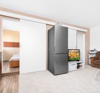 Living room with a sofa, television, cabinet, and kitchenette in a 3-room apartment.