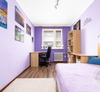 The purple room with a table, bed, and decorations in the 3-room apartment has a floor with a wooden decor.