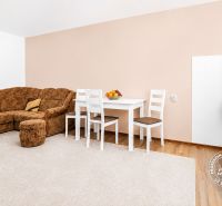 Living room with a corner sofa, white table, and floor with wood decor.