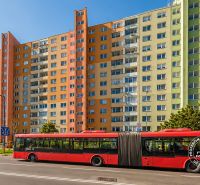 A colorful panel apartment building on Námestie hraničiarov, Bratislava - Petržalka, with a red bus in front of it.