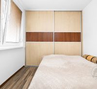 A bedroom in a 3-room apartment with a large wardrobe system and a floor with a wooden decor.