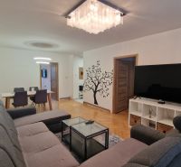 Living room with a large TV, gray sofa, and wooden decor flooring in a 3-room apartment.