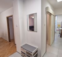 A hallway in a 3-room apartment with a wooden decor floor and a table in the background.