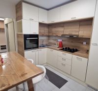 A kitchen in a 3-room apartment with a corner unit and flooring with a wood decor.