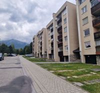 Apartment building on Pod lesom Street, Vysoké Tatry, surrounded by mountains and parked cars.