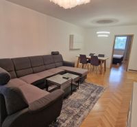 Spacious living area in a 3-room apartment with a sofa and a dining table, floor with wood decor.