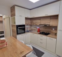 A kitchen in a 3-room apartment with white cabinets and wood decor.