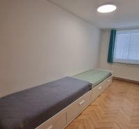 A room in a 3-room apartment with two beds and a floor with a wooden decor.