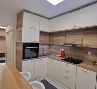 A kitchen in a 3-room apartment with a wooden decor and built-in appliances.