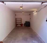 Simply furnished garages on Partizánska Street in Trenčín with shelving and lighting.