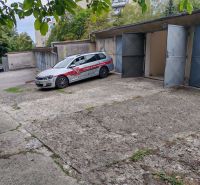 Garages on Partizánska Street in Trenčín with a parked car and an open garage.