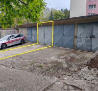 Garages on Partizánska Street in Trenčín, with a car parked under a tree nearby.
