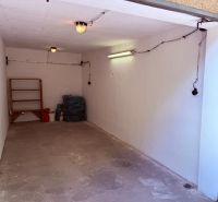Inside the garage, there is a concrete floor, a shelf, and ceiling lighting.