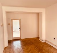 A room in a 2-room apartment with a wooden decor floor and glass doors.