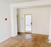 A room with a wooden decor floor and glass doors in a two-room apartment.