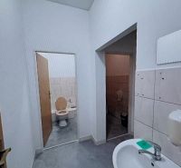 Sink and toilet in offices with white tiles and gray flooring.