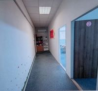 A narrow hallway in an office with doors marked with numbers on the right.