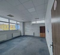 A spacious office with carpeted flooring and large windows.