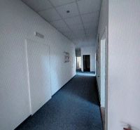 A narrow hallway with light walls and carpet in an office.