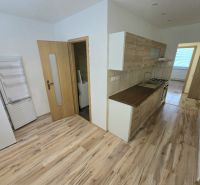A kitchen in a 3-room apartment with a wood-patterned floor and appliances.