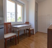 A kitchen in a 3-room apartment with a wooden decor floor, a table, and chairs.