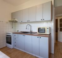 A kitchen in a 3-room apartment with a microwave, stove, and wooden decor flooring.