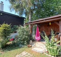 A house on Do Žlebín Street in Ružomberok, surrounded by greenery and a wooden gazebo.