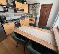 A kitchen with light cabinets and a wood-patterned floor in a three-room apartment.