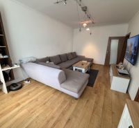 Living room in a 3-room apartment with a sofa and a television, floor with wooden decor.