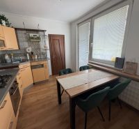 A kitchen in a 3-room apartment with a corner unit and a floor with a wood decor.