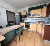 A kitchen in a 3-room apartment with a wooden decor floor and a dining table.