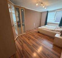 A bedroom in a 3-room apartment with a wood-decor floor and a large built-in wardrobe.