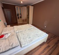 A bedroom with a wood-patterned floor and a built-in wardrobe in a three-room apartment.
