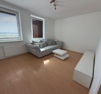 Living room with a sofa and a table in a 2-room apartment, floor with wooden decor.
